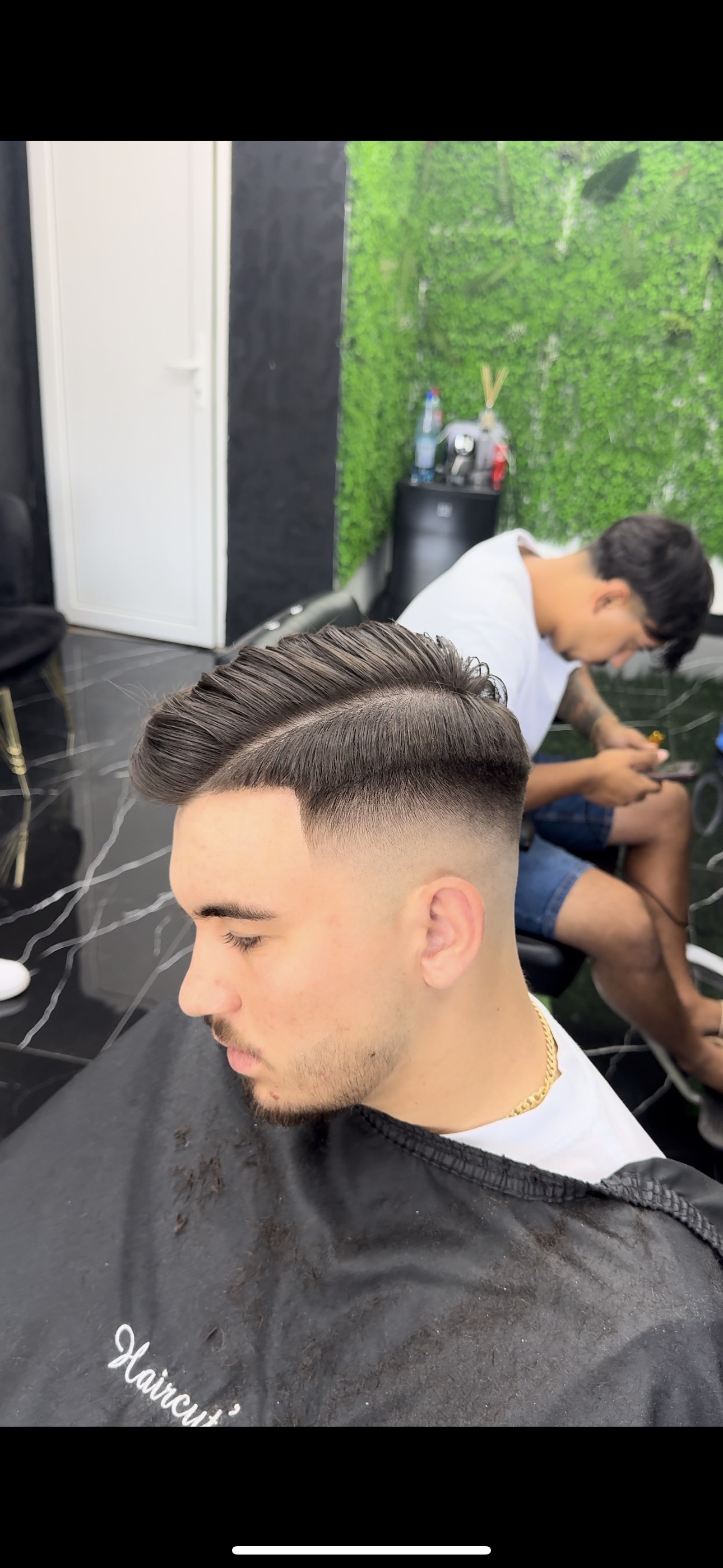 Client al frizeriei cu o tunsoare de tip Fade si parul de culoare verde